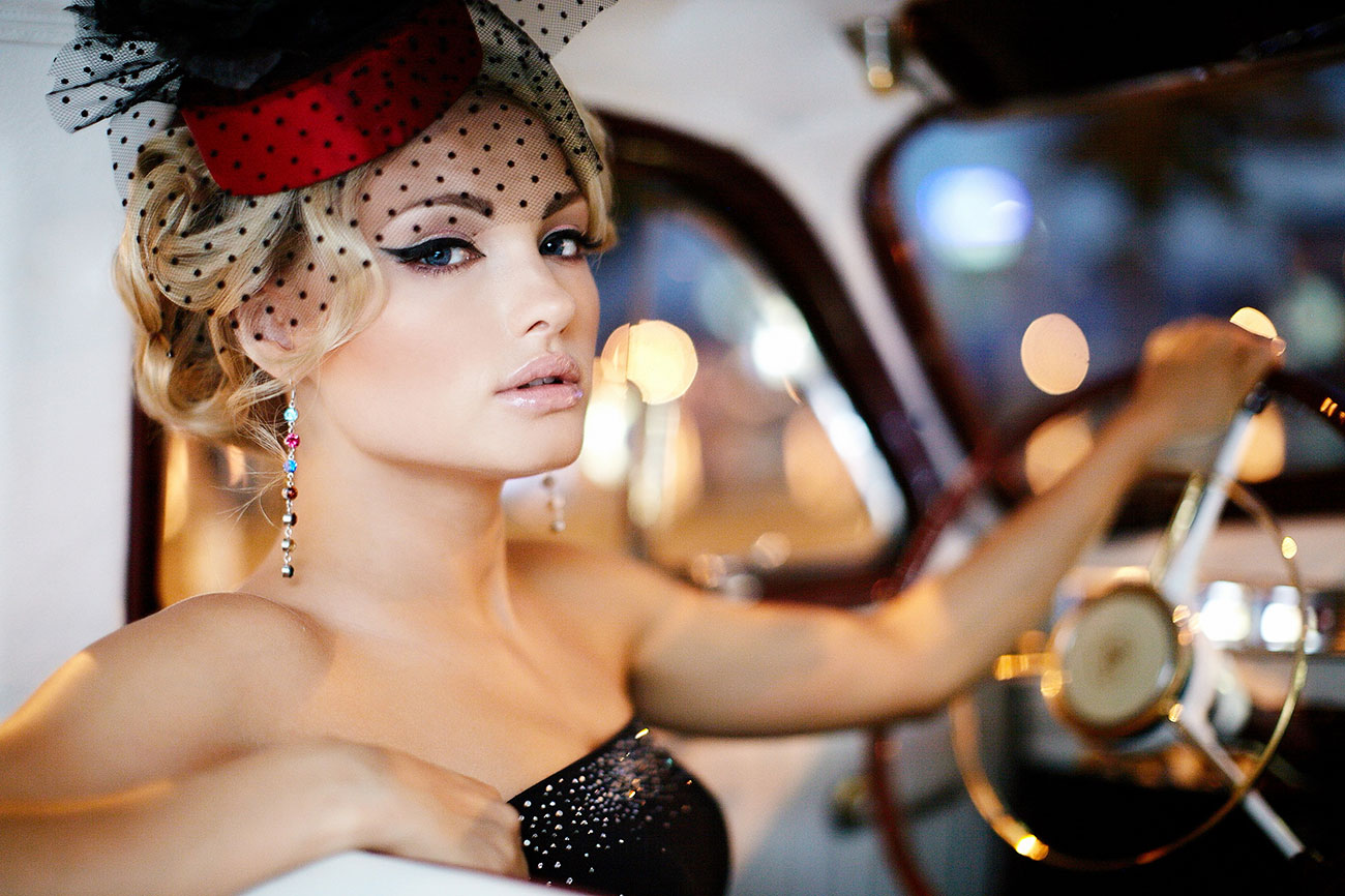Elegant woman wearing fascinator in vintage car