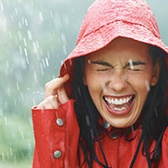 Woman laughing in red raincoat in rain Woman laughing in red raincoat in rain